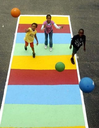 Students playing shuffle board at recess with new playground equipment and court.